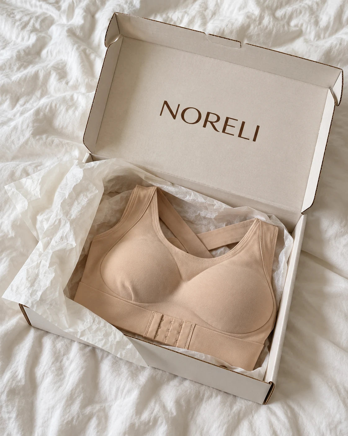 NORELI beige bra in a cream branded box on white bedding.